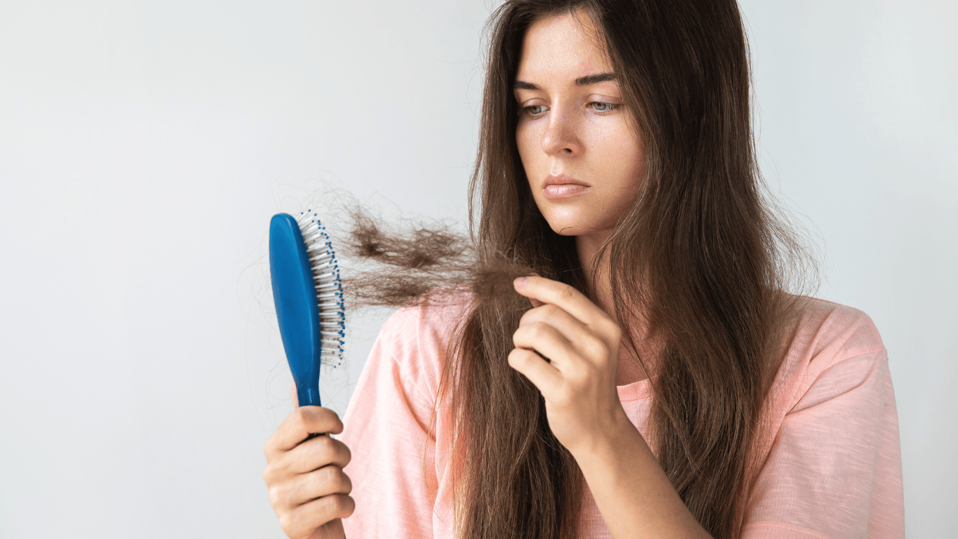 mujer mirando el peine porque se le cae el cabello debido al cambio de estacion